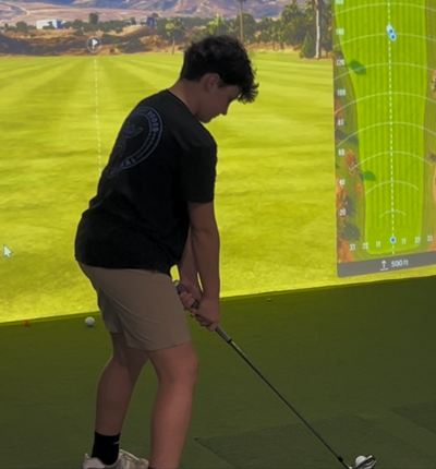 Young golfer hitting a shot in a TrackMan golf simulator bay at Grip It & Rip It Golf in Palestine Texas